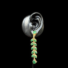 A stunning pair of cascading earrings featuring lush green emerald-like stones set in a delicate gold-tone vine design.