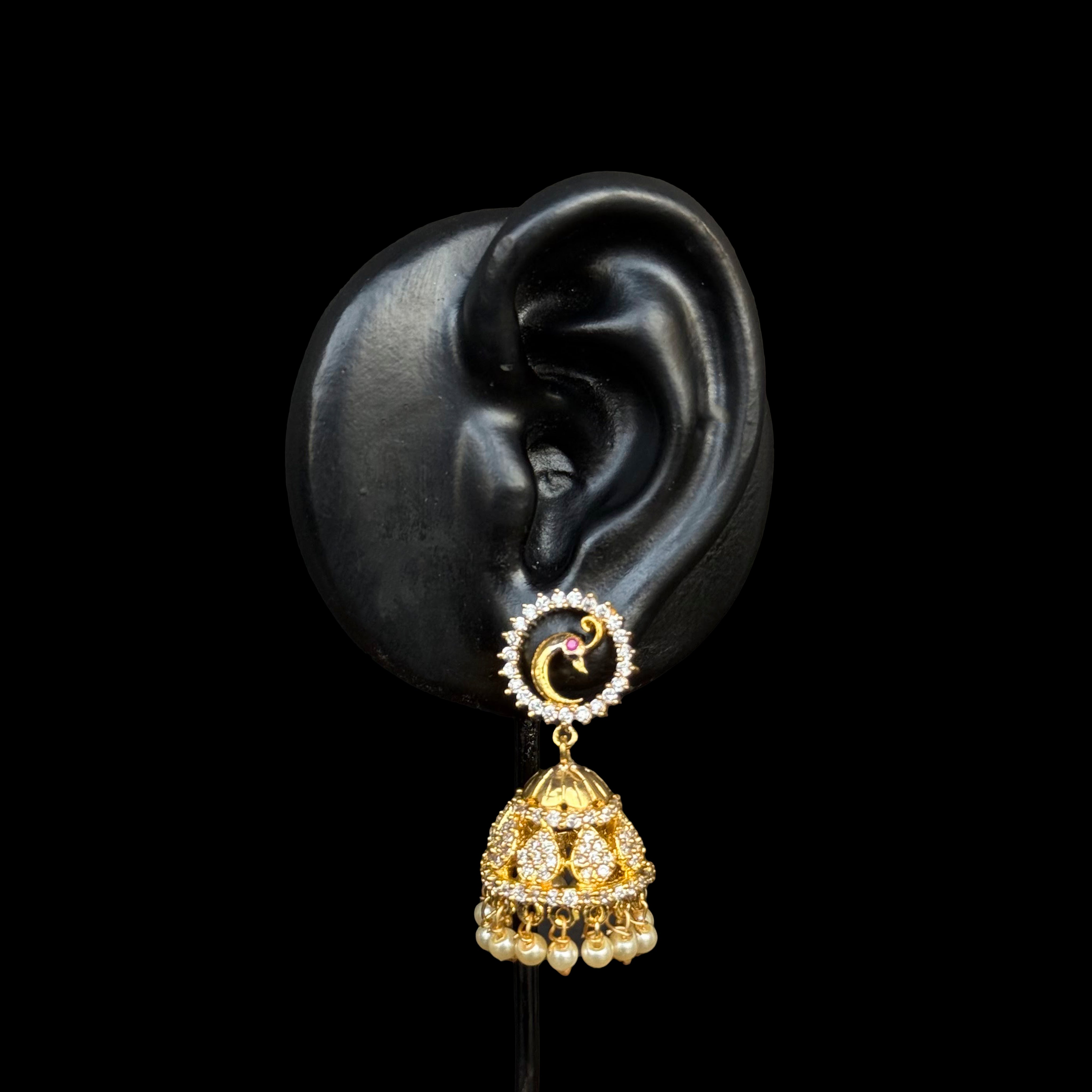 A celestial blend of moon and star motifs, these dazzling gold-plated jhumkas feature an intricate circular stud with a tiny ruby accent and a traditional jhumka adorned with pearls and stones.